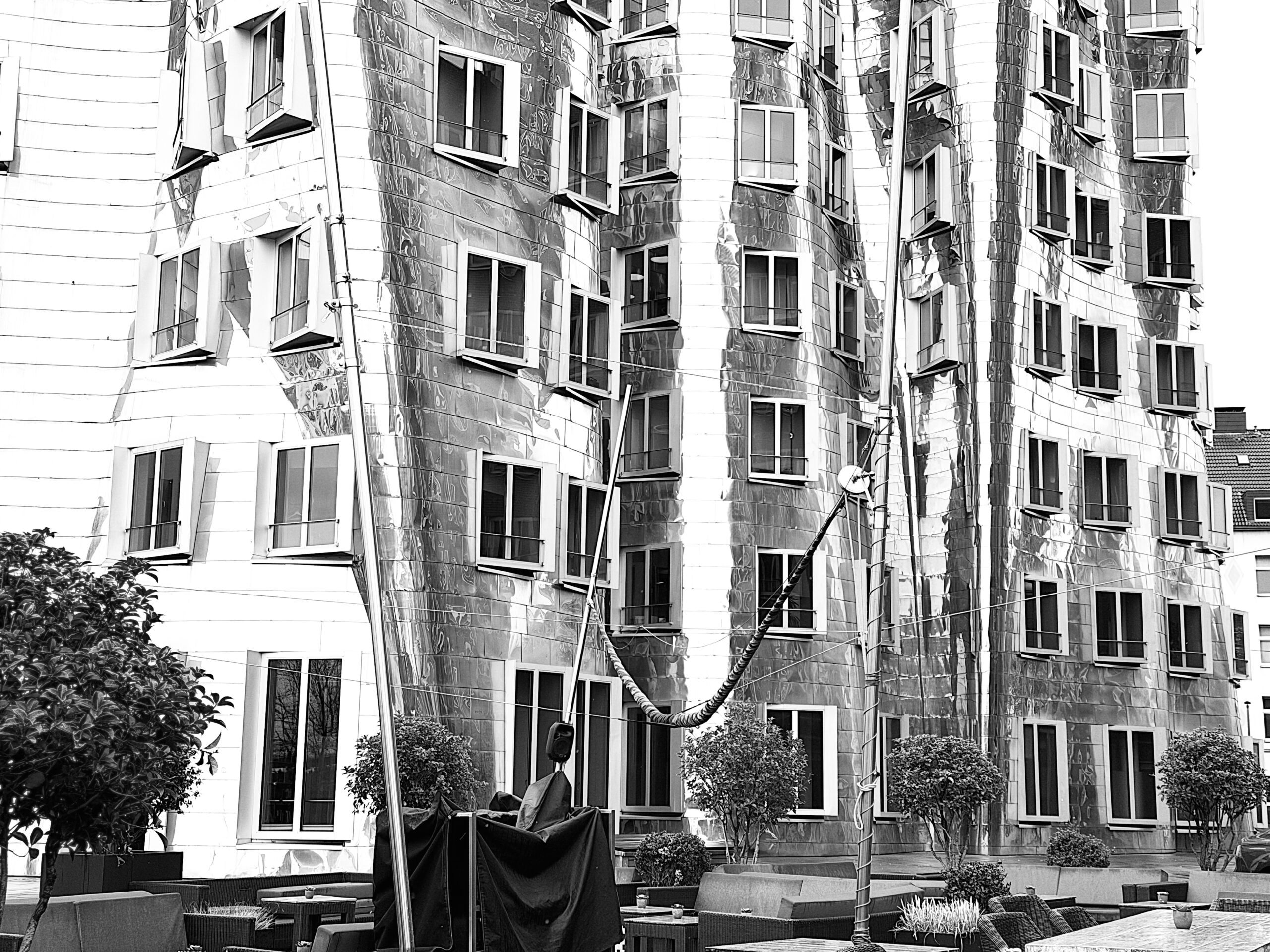 Neuer Zollhof中央棟のステンレス外装と歪んだ窓配置を捉えた寄りの写真